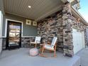 Inviting covered front porch with stylish rocking chairs and a stone facade at 26293 E Archer Ave, Aurora, CO 80018