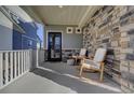 Inviting front porch featuring stylish rocking chairs and stone accents, perfect for relaxing at 26293 E Archer Ave, Aurora, CO 80018