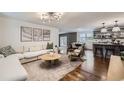 Open-concept living room with modern lighting, hardwood floors, and seamlessly connected to the dining and kitchen areas at 7746 S Gray St, Littleton, CO 80128