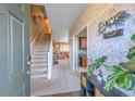 Inviting foyer featuring a staircase, decorative wallpaper, and an open view into the living spaces at 25262 E 2Nd Pl, Aurora, CO 80018