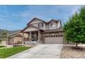 Attractive two-story house showcases a covered porch, stone detailing, a driveway, and a low-maintenance landscaped yard at 22583 E Union Cir, Aurora, CO 80015