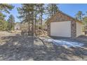 Exterior of detached two-car garage with stone accents, and view of the house in the background at 8390 E Summit Rd, Parker, CO 80138