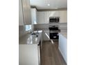 Close-up of the kitchen with stainless steel appliances, light countertops, white cabinets, and a sink at 21996 E 39Th Pl, Aurora, CO 80019