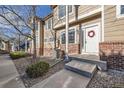 Inviting townhome entrance with brick accents, concrete steps and walkway, and a festive wreath at 6845 S Webster St # G, Littleton, CO 80128