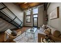 Bright living room with high ceilings, exposed brick, modern staircase, hardwood floors and large windows at 1111 Osage St # 23, Denver, CO 80204