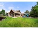 Expansive backyard with lush lawn, a covered patio, and a play area, perfect for outdoor fun at 5886 Amber Ridge Dr, Castle Pines, CO 80108