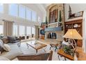 Bright living room featuring a stone fireplace, high ceilings, large windows, and sliding doors at 5886 Amber Ridge Dr, Castle Pines, CO 80108