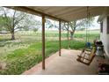 A covered patio with a porch swing offers a tranquil outdoor space overlooking the open fields beyond the fenced property at 2091 Tate Ave, Fort Lupton, CO 80621