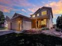 Charming two-story home with a well-manicured lawn and flower beds at twilight at 14191 W Amherst Ave, Lakewood, CO 80228