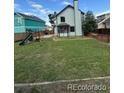 Spacious backyard featuring lush green grass, a sturdy wooden fence, and a playground area for endless outdoor fun at 4362 Denmark Ct, Denver, CO 80239