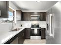 Modern kitchen featuring stainless steel appliances, dark cabinets, and white countertops at 5993 Oneida St, Commerce City, CO 80022