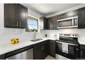Updated kitchen featuring dark cabinets, stainless steel appliances, and a bright window at 5993 Oneida St, Commerce City, CO 80022