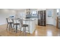 Modern kitchen with stainless steel appliances, a center island with bar stools, and hardwood floors at 4410 S Estes St, Littleton, CO 80123