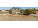 Landscaped front yard featuring mature trees, lush green lawn, and tiered brick retaining wall at 8700 Ehler Pkwy, Brighton, CO 80602