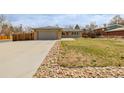 A single-story home with a concrete driveway, rock-lined landscaping, and a lush green lawn at 396 Tucson St, Aurora, CO 80011