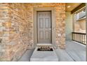 Closeup of the front door with a stone facade and a 'Hello Goodbye' welcome mat at 6591 N Ceylon St, Denver, CO 80249