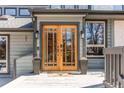 Elegant wooden double doors welcome you to this beautiful home, framed by stylish planters and modern lighting at 8277 Carriage Ln, Parker, CO 80134