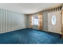 Bright living room with blue carpet, striped wallpaper, a front door and window with view of snow outside at 3052 S Joplin Ct, Aurora, CO 80013