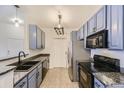 Galley kitchen showcasing blue cabinets, granite countertops, and stainless steel appliances at 9180 Rolling Way # 303, Parker, CO 80134