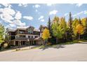 Exterior view of a condo with balconies and fall foliage, on a sunny day with a blue sky at 655 Four O Clock Rd # 104, Breckenridge, CO 80424