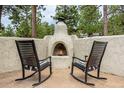Inviting outdoor area featuring a stone fireplace and comfortable rocking chairs at 17995 Minglewood Trl, Monument, CO 80132