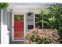 Close-up of a red front door with house number and flowering bushes in front of the property at 5523 E Utah Pl, Denver, CO 80222