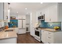 Bright kitchen featuring white cabinetry, stainless steel appliances, and a beautiful blue tiled backsplash at 5523 E Utah Pl, Denver, CO 80222