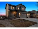 Charming two-story home showcasing a covered porch, three-car garage, and manicured front yard with decorative tree at 12863 Crane River Dr, Firestone, CO 80504