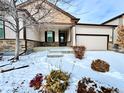 Charming home with a two-car garage and inviting front entrance during a winter snowfall at 12213 Joplin St, Commerce City, CO 80603