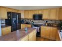 Well-lit kitchen with wooden cabinets, black appliances, and a center island at 8024 W 95Th Way, Broomfield, CO 80021