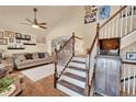 Bright foyer showcasing hardwood floors, a staircase, and living room with a ceiling fan at 14558 Vine St, Thornton, CO 80602