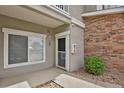 Front door entrance featuring brick accents, pea gravel landscaping, and manicured bushes at 1801 S Dunkirk St # 108, Aurora, CO 80017