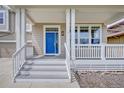 Inviting front porch with a bright blue door, white railings, and ample natural light at 8545 Braun Loop, Arvada, CO 80005