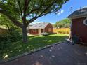 Large backyard featuring green grass, trees, privacy fence, and a storage shed at 1273 S Jackson St, Denver, CO 80210