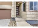 Front entrance featuring a modern front door with glass panels, set of steps, and beige siding at 10808 Salida St, Commerce City, CO 80022