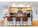 Well-lit kitchen with central island, stainless appliances, light wood cabinetry, and hardwood floors at 2240 N Clay St # 501, Denver, CO 80211