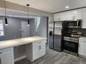 Well-lit kitchen featuring white cabinets, stainless steel appliances, a large island and gray plank flooring at 8954 N Carr Cir, Broomfield, CO 80021