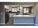 Open-concept kitchen boasts an island with white cabinets, stainless steel appliances, and gray plank flooring at 8954 N Carr Cir, Broomfield, CO 80021