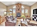 A living room featuring a stone fireplace, vaulted ceilings, and multiple windows with views at 15125 Spring Valley Rd, Larkspur, CO 80118