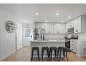 Modern kitchen boasts white cabinets, stainless steel appliances, island with seating, and bright lighting at 1143 Hummingbird Cir, Longmont, CO 80501