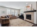 Comfortable living room with a stone fireplace, abundant natural light, and a cozy seating area at 7968 E 152Nd Dr, Thornton, CO 80602