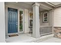 Inviting front porch featuring a blue front door, gray pillars, and stylish decor at 8783 S Winnipeg Ct, Aurora, CO 80016