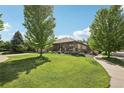 Landscaped front yard featuring a charming covered porch and beautiful greenery, enhancing the home's curb appeal at 2864 S Jebel Way, Aurora, CO 80013