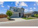 Inviting home with gray siding, a two-car garage, green lawn, and charming landscaping at 6954 E 117Th Ave, Thornton, CO 80233