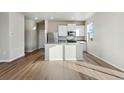 Modern kitchen features white cabinets, stainless appliances, island with sink and hardwood flooring at 2974 Oxley St, Strasburg, CO 80136
