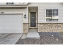Welcoming front entrance with stone accents, a black front door with wreath, and tidy landscaping at 13362 Amber Sky St, Parker, CO 80134