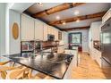 Modern kitchen with sleek black countertops, brick backsplash, wooden beams, and stainless steel appliances at 10528 Applebrook Cir, Highlands Ranch, CO 80130