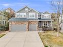 Attractive two-story home with a stone and gray facade, a three-car garage, and a well-maintained lawn at 7329 Arco Iris Ln, Castle Pines, CO 80108