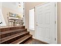 Bright entryway featuring hardwood stairs leading to a dining area with natural light and a white front door at 1622 Dyer Loop, Brighton, CO 80603