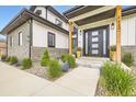 Modern home entrance featuring an elegant door, exterior lighting and manicured landscaping at 8623 S Wadsworth Ct, Littleton, CO 80128